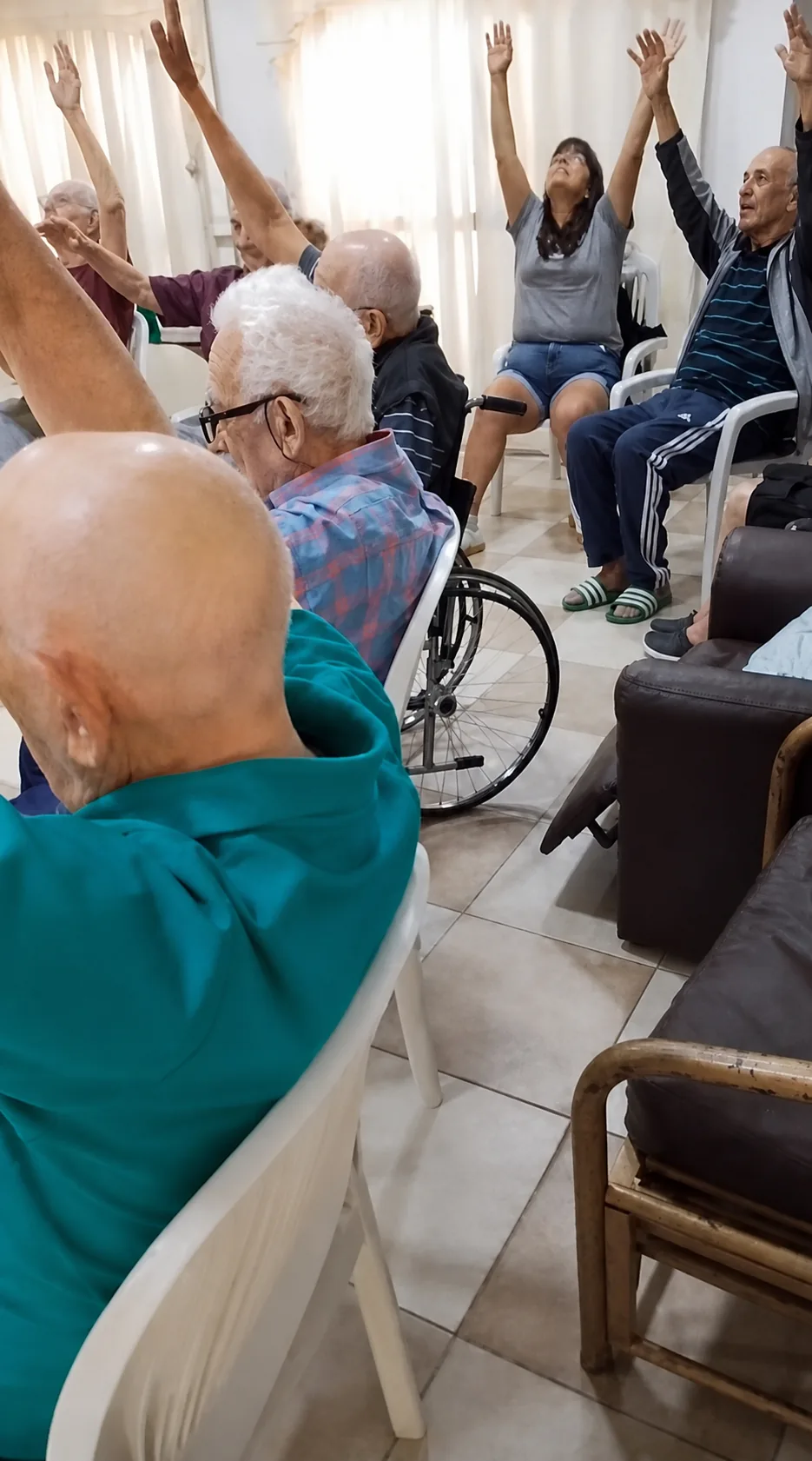 Residentes participando de una actividad de gimnasia con brazos elevados