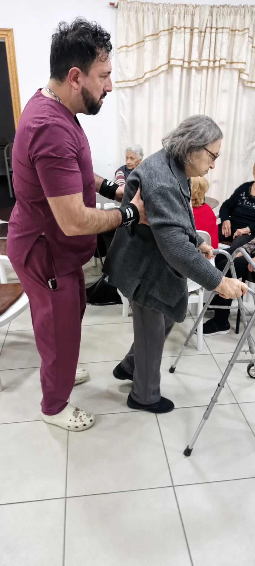 Kinesiólogo acompañando a una residente durante ejercicios con andador